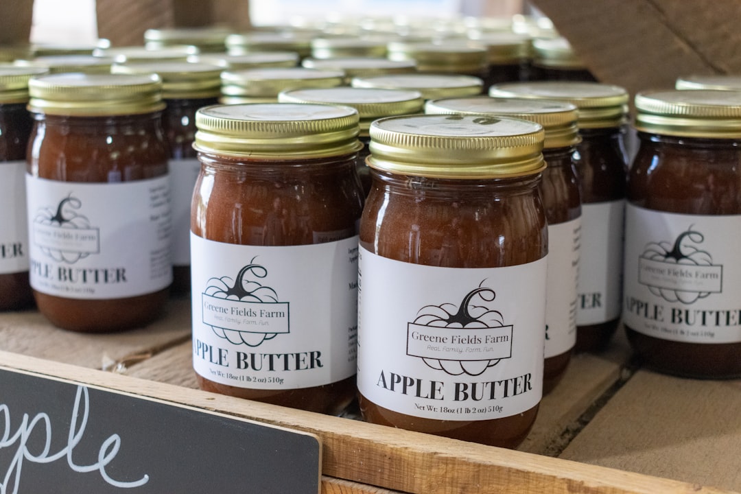 Rows of sealed home-canning jars filled with apple butter on a wooden shelf