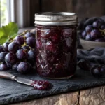 Jar of chunky whole grape preserves with purple grapes
