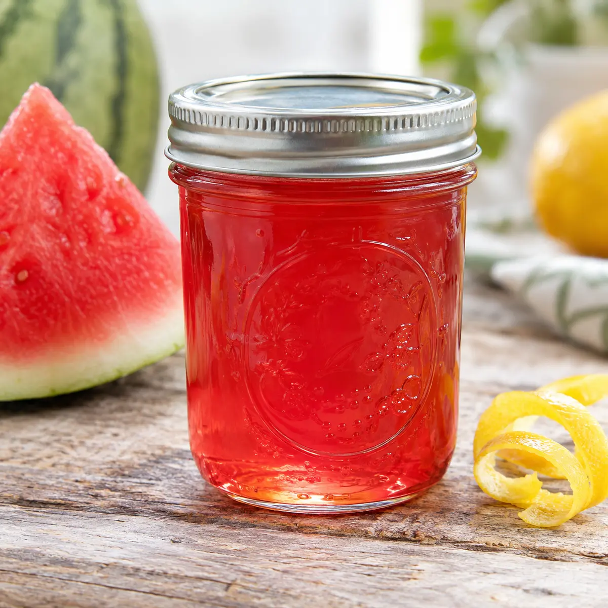 Jar of bright watermelon jelly with a fresh watermelon wedge